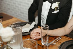 bride and groom hold hands during speeches at Tire Shack Brewery, intimate elopement photographer in Moncton New Brunswick, editorial vibes
