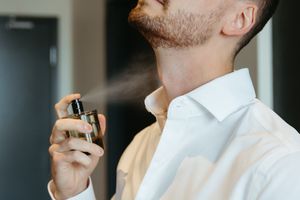 candid getting ready moment, groom sprays cologne, wedding portraits in Moncton New Brunswick, luxury wedding photographer in Canada