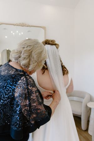 Mother of the bride helps bride into wedding dress in bridal suite, The Algonquin resort wedding St. Andrew's wedding photography packages