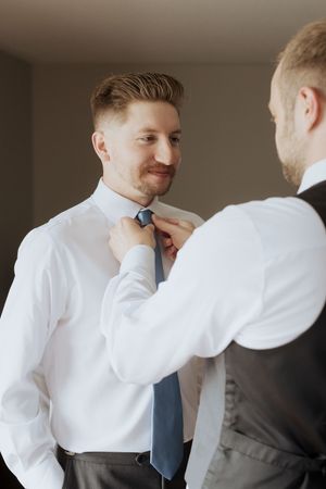 Groomsmen helping groom tie his tie, getting ready photography at Fredericton wedding. Timeless true to life wedding photography