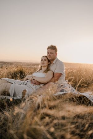 Romantic couple embracing in a golden field during sunset.
