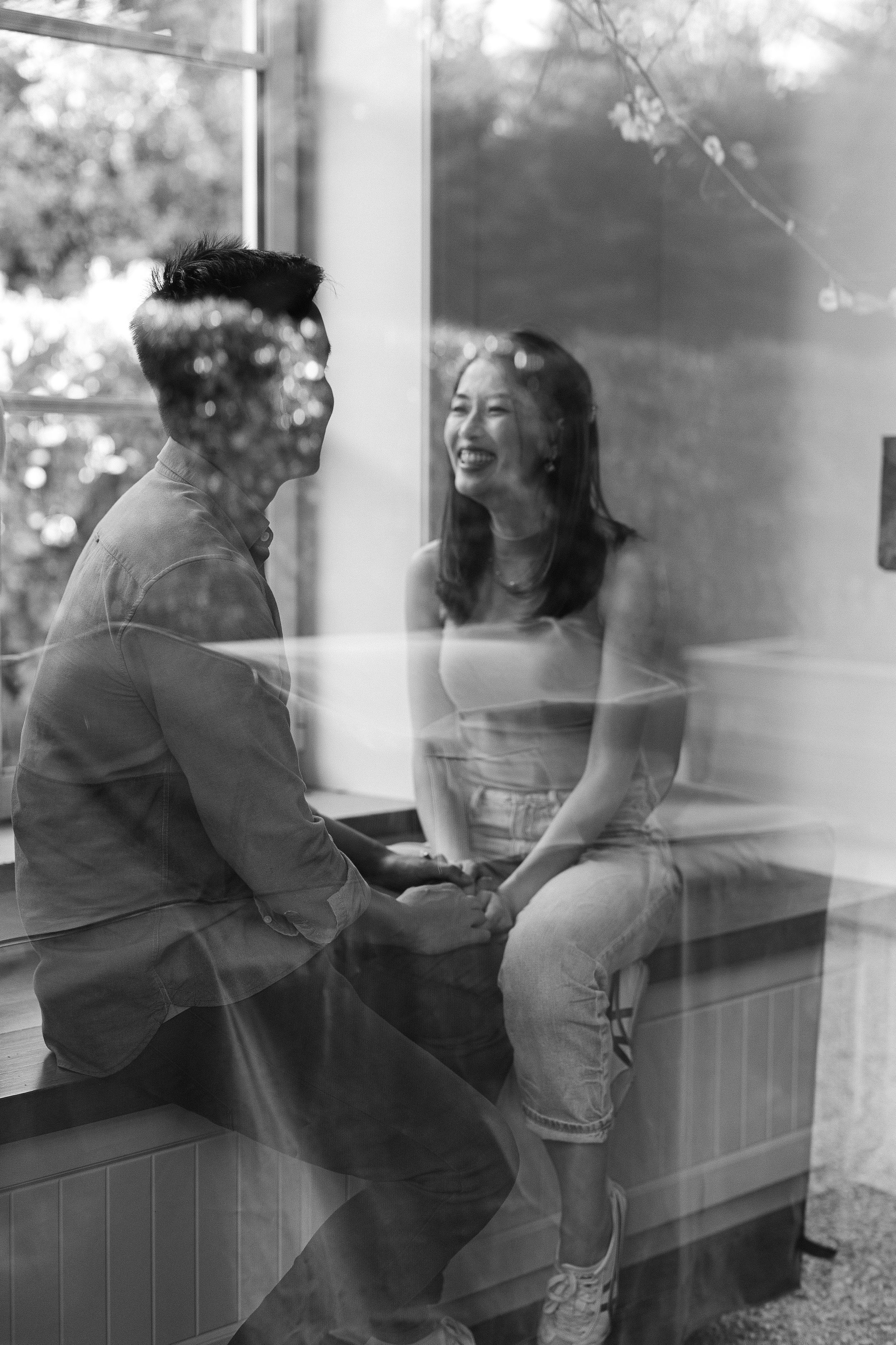 A couple sharing a tender moment by a window with soft natural light filtering through.