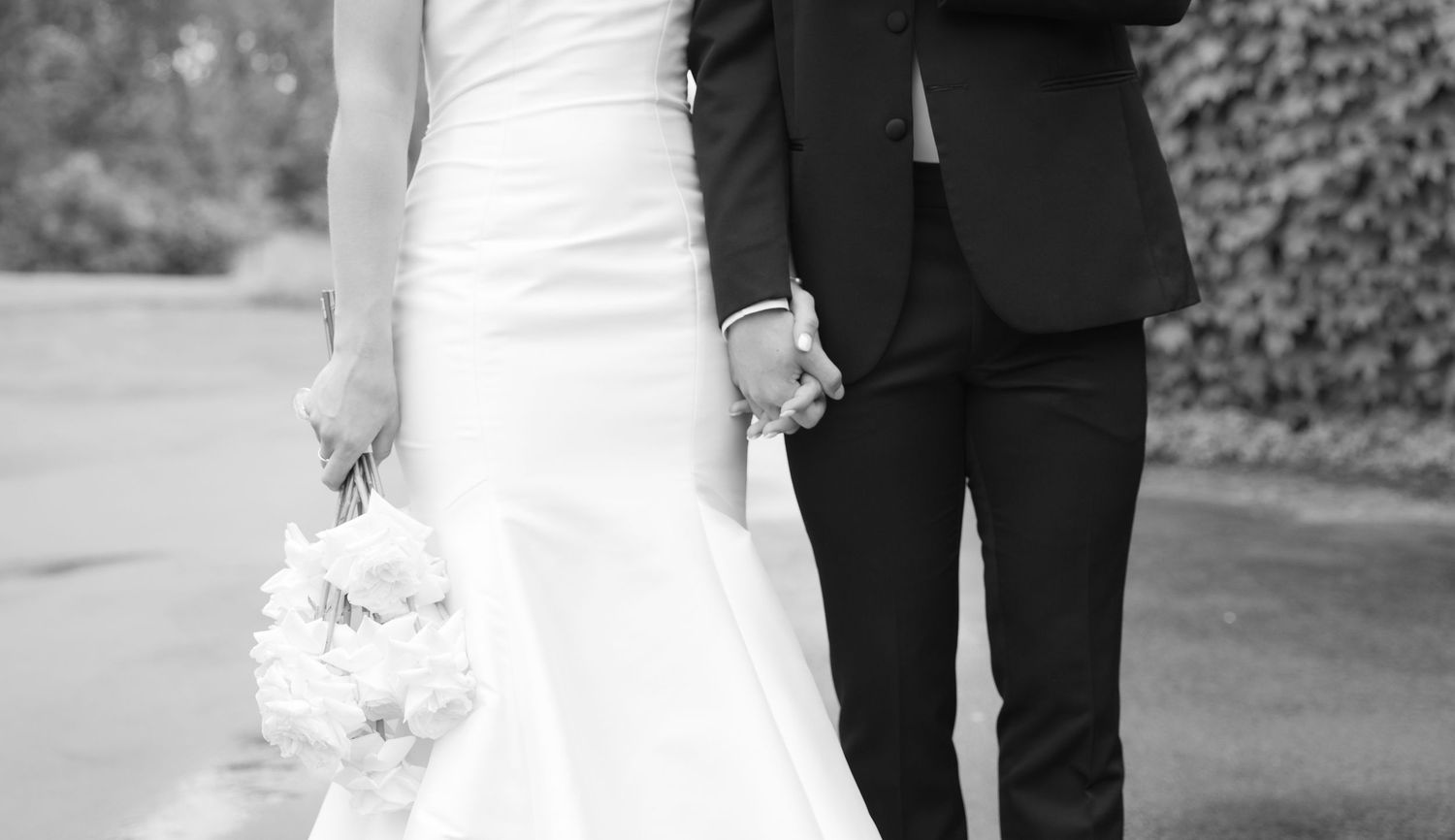 Black and white wedding photo showing formal attire and a bridal bouquet.