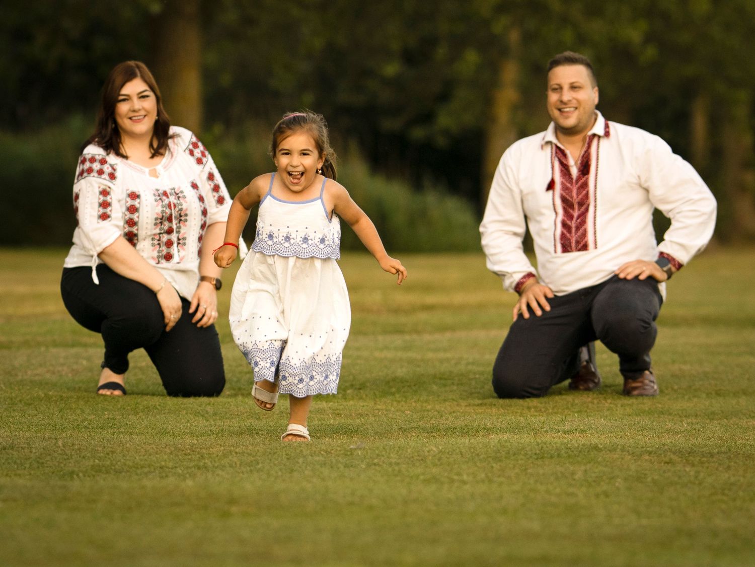 People relaxing on a sunny grass lawn wearing traditional embroidered clothing.