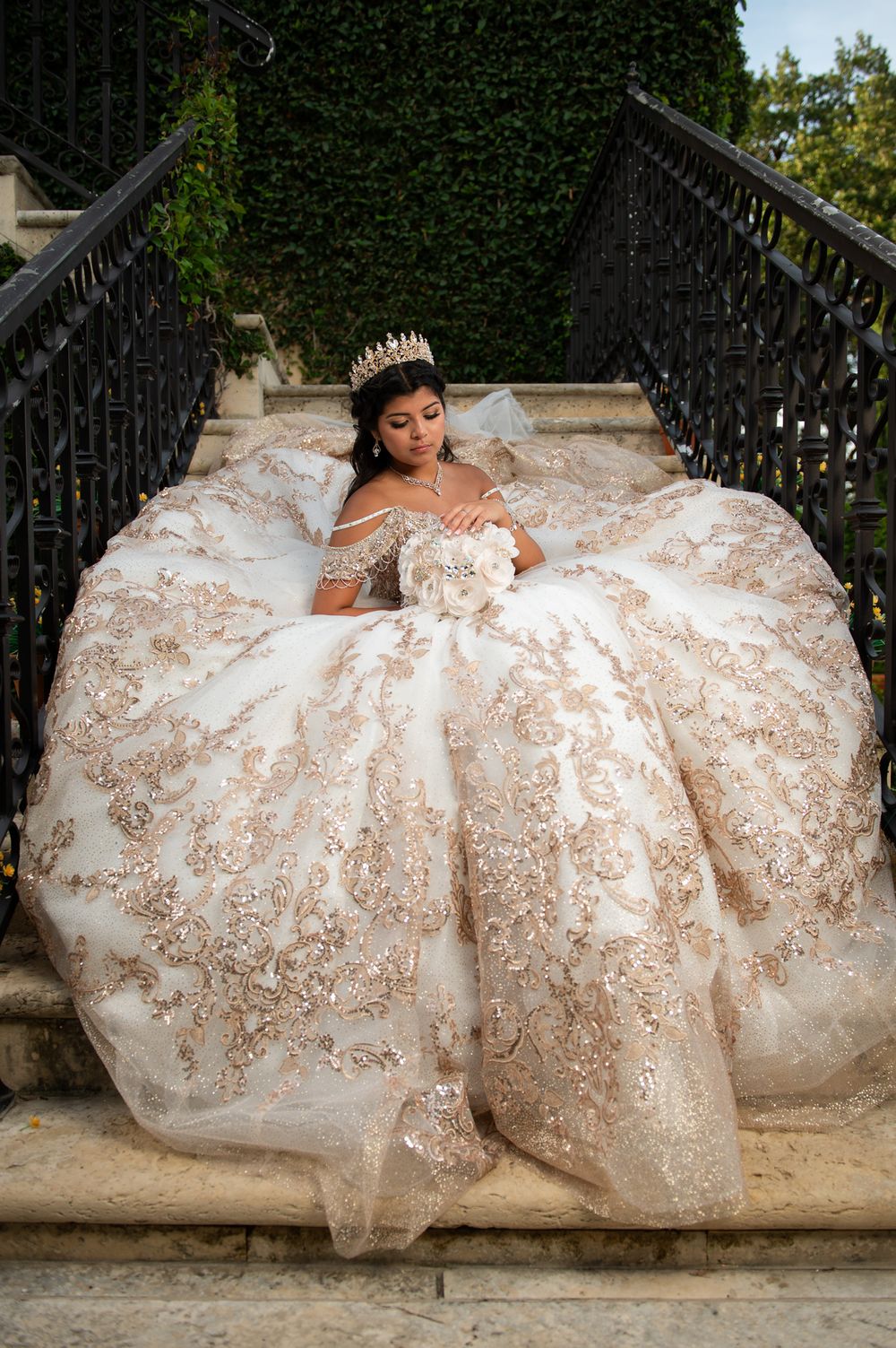 Ornate ballgown with golden details spreads dramatically across stone steps.
