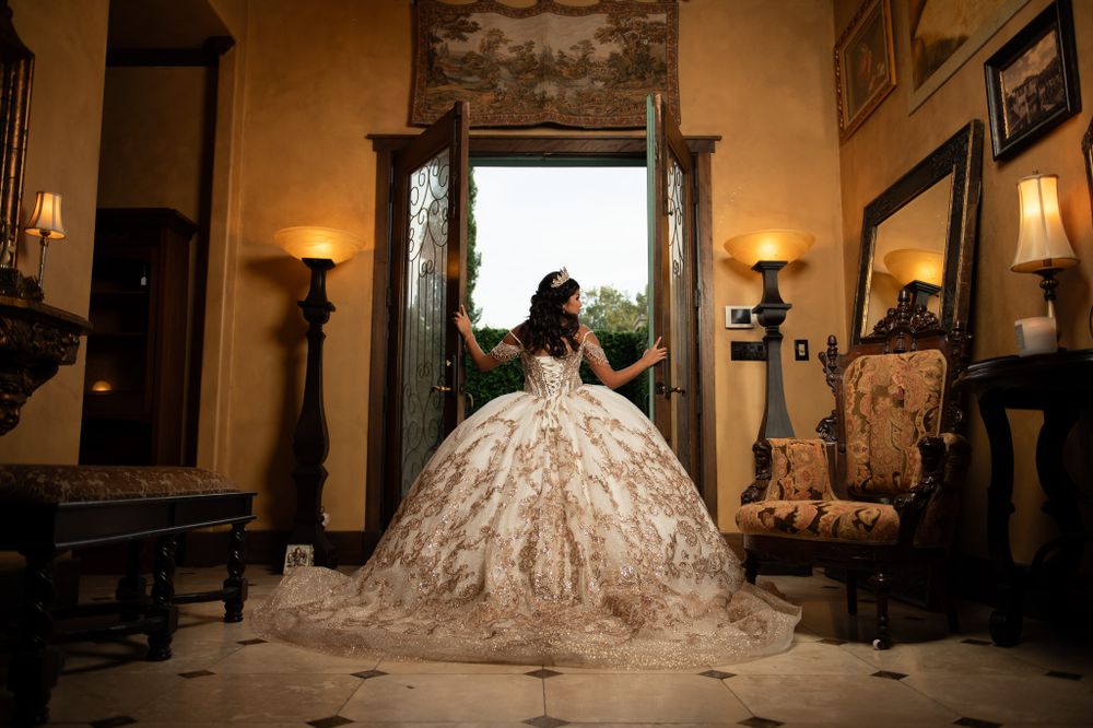 A dramatic full-skirted wedding dress captured in a doorway with warm lighting.