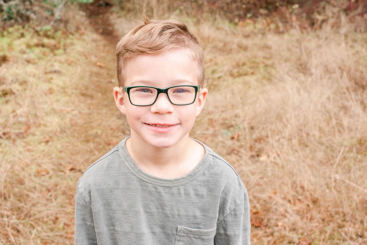 Close up portrait of youth wearing glasses against autumn foliage.