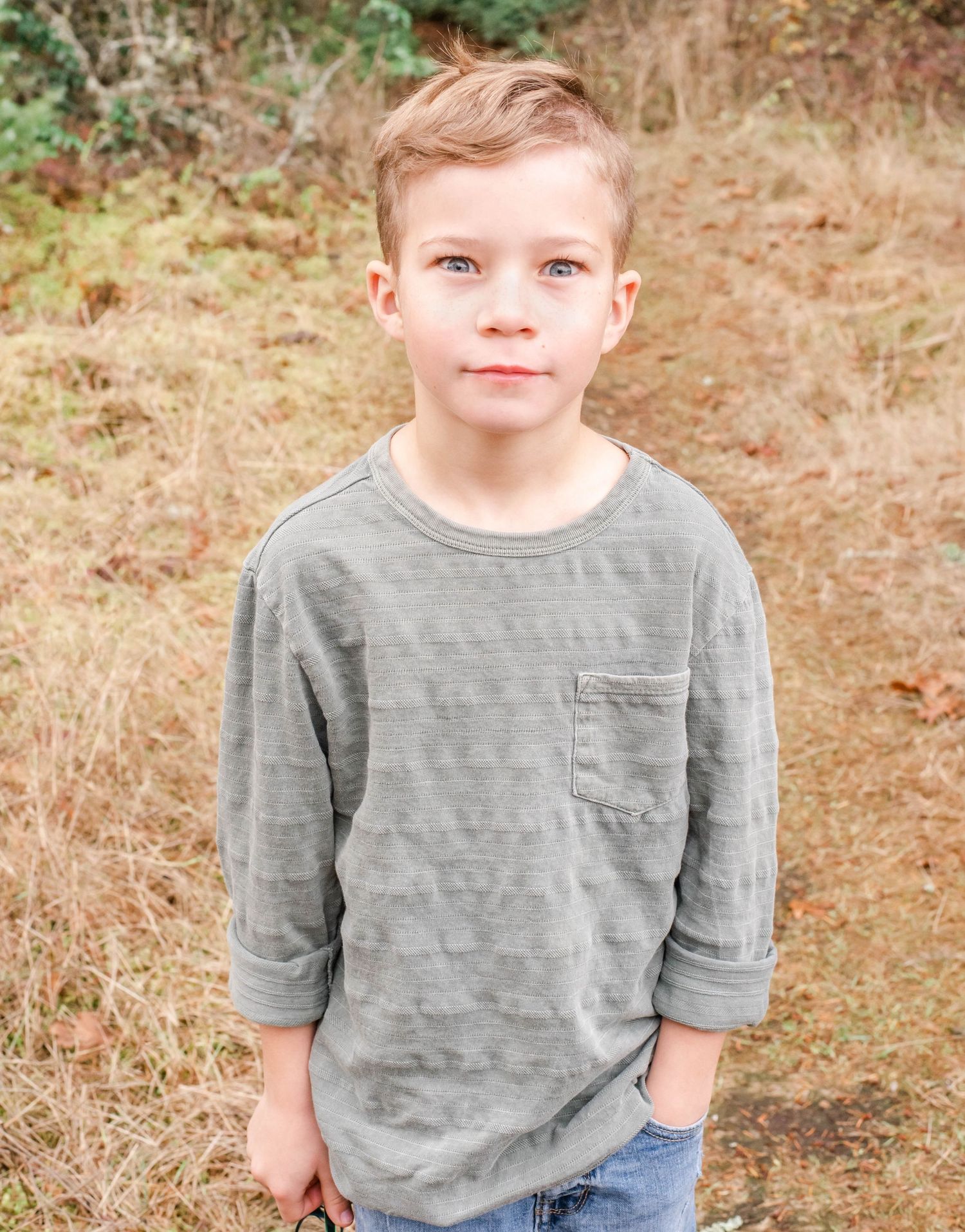 Portrait of young person in gray t-shirt against natural brown background.
