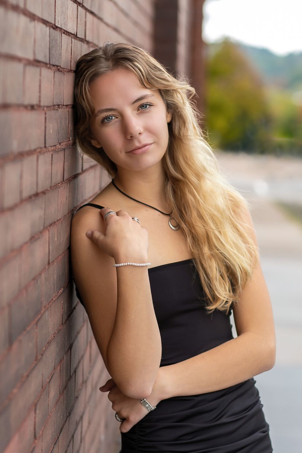 Series of casual portraits against brick wall wearing black tank top.