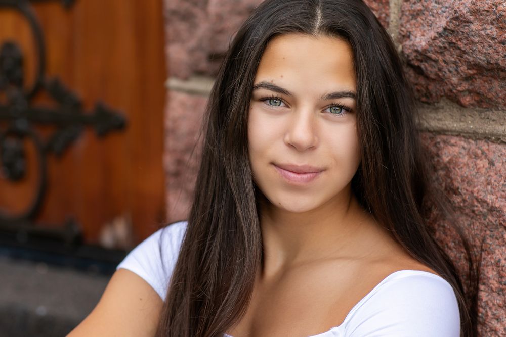 Portrait series against textured red brick wall in natural lighting.