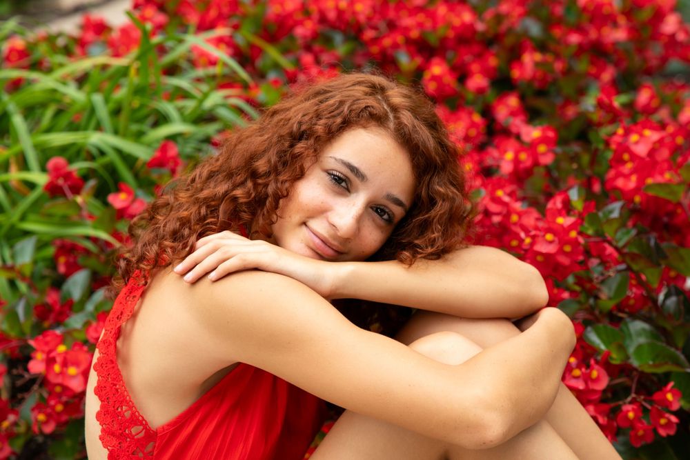 Portrait series among vibrant red flowers in outdoor garden setting.