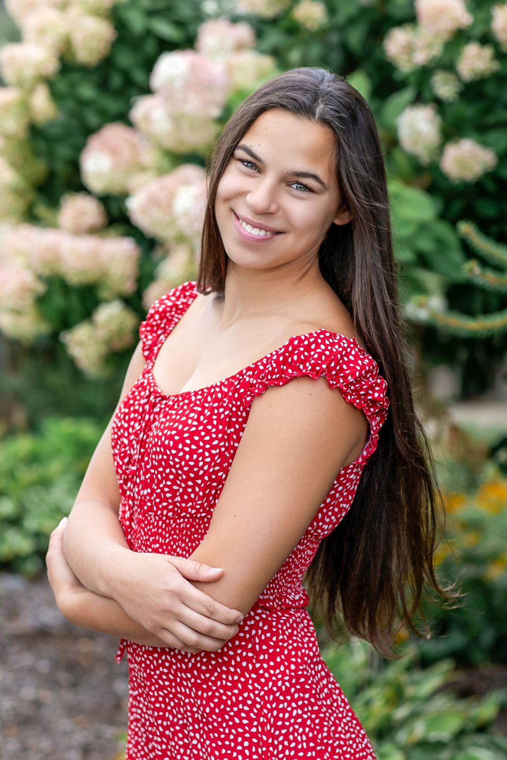 Portrait series in garden with blooming roses featuring red polka dot dress.