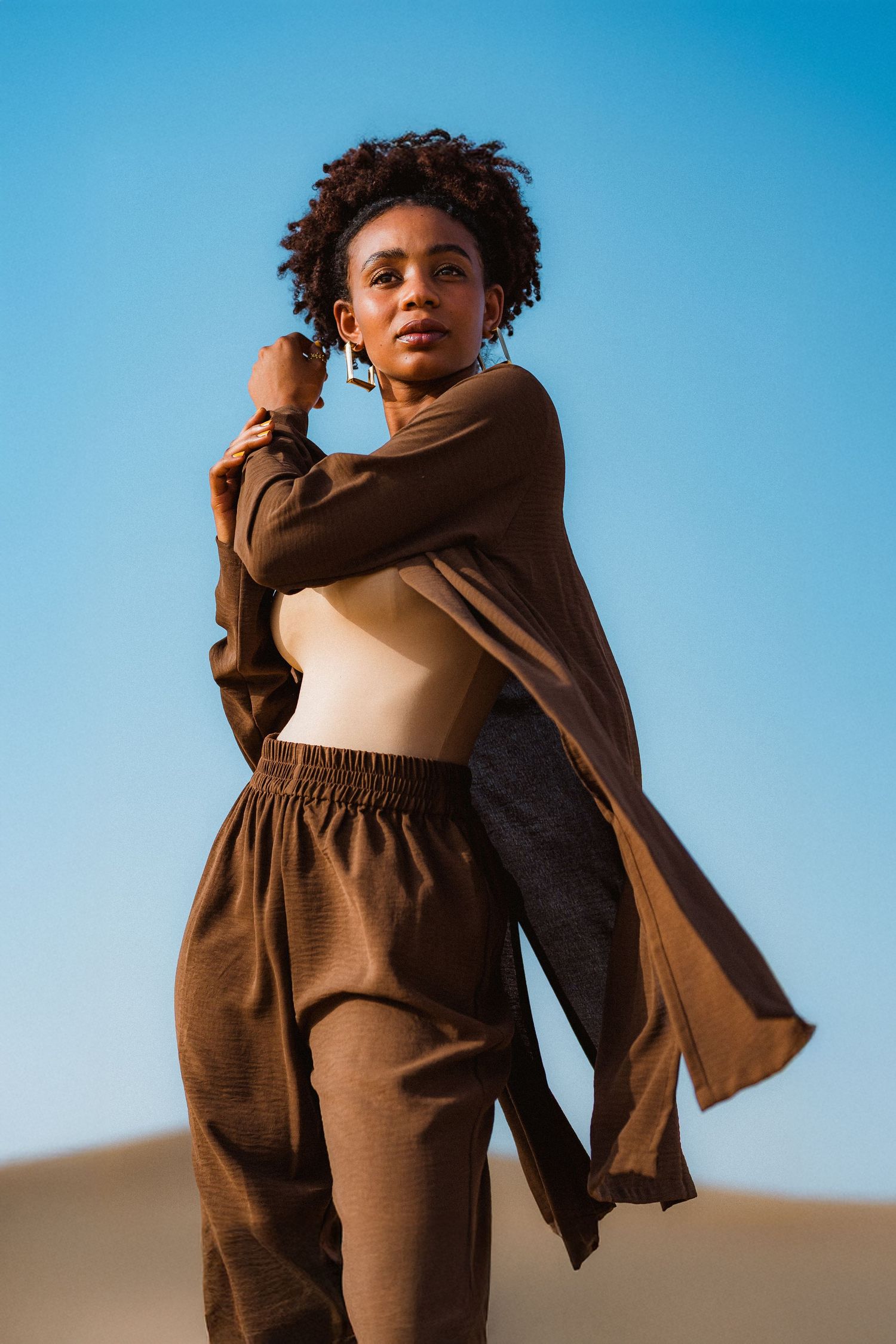 Editorial fashion photography in Dubai desert with flowing brown outfit