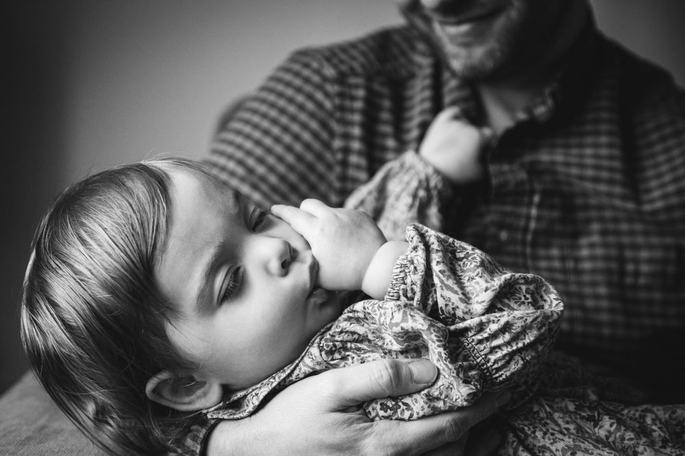 An intimate black and white moment of a resting baby with a caregiver.