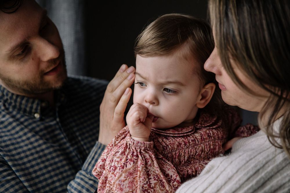 Tender family moment with soft lighting and pink knit clothing.