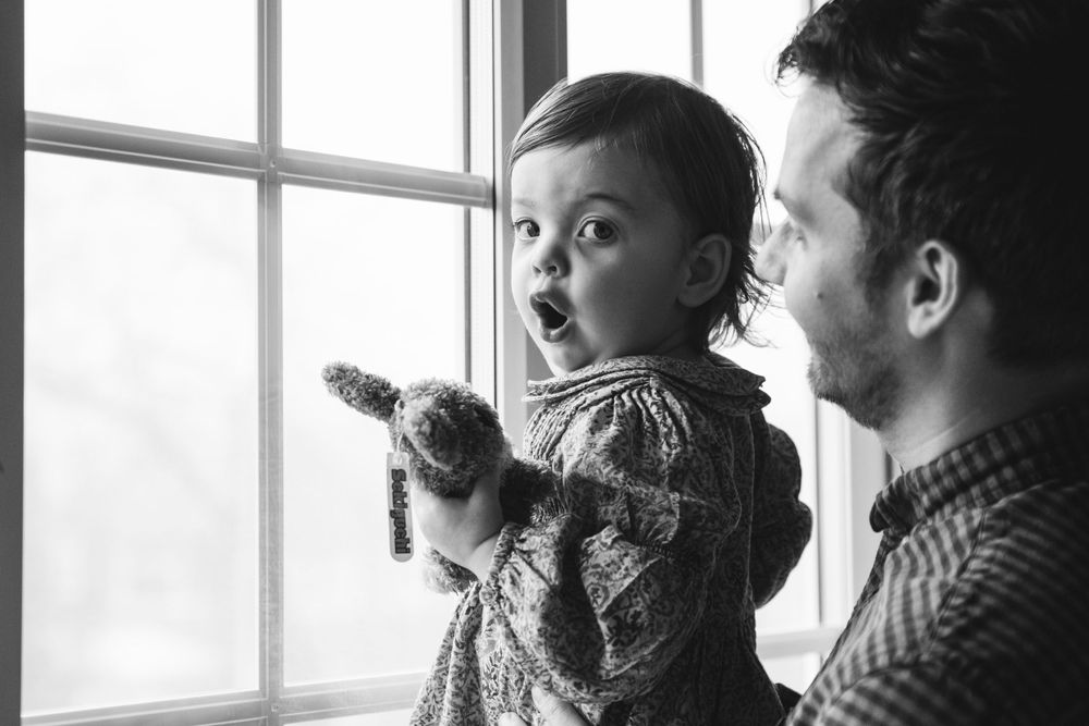 Looking out a window with excitement while wearing a patterned sweater.