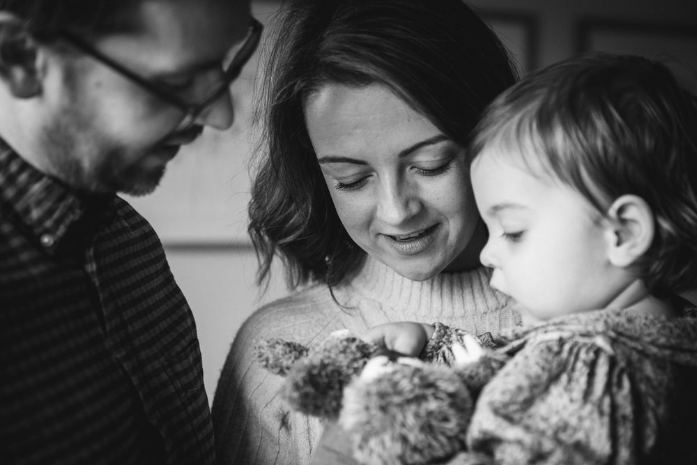 Black and white family photo showing intimate moment between caregivers and baby.