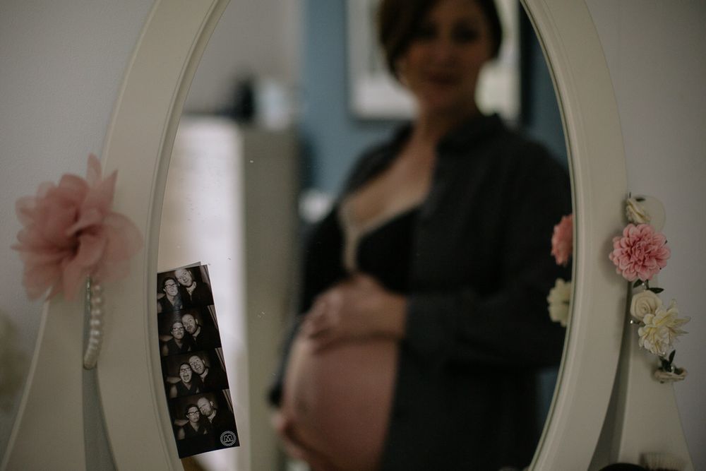 A mirror reflection captures a maternity moment with delicate floral decorations.