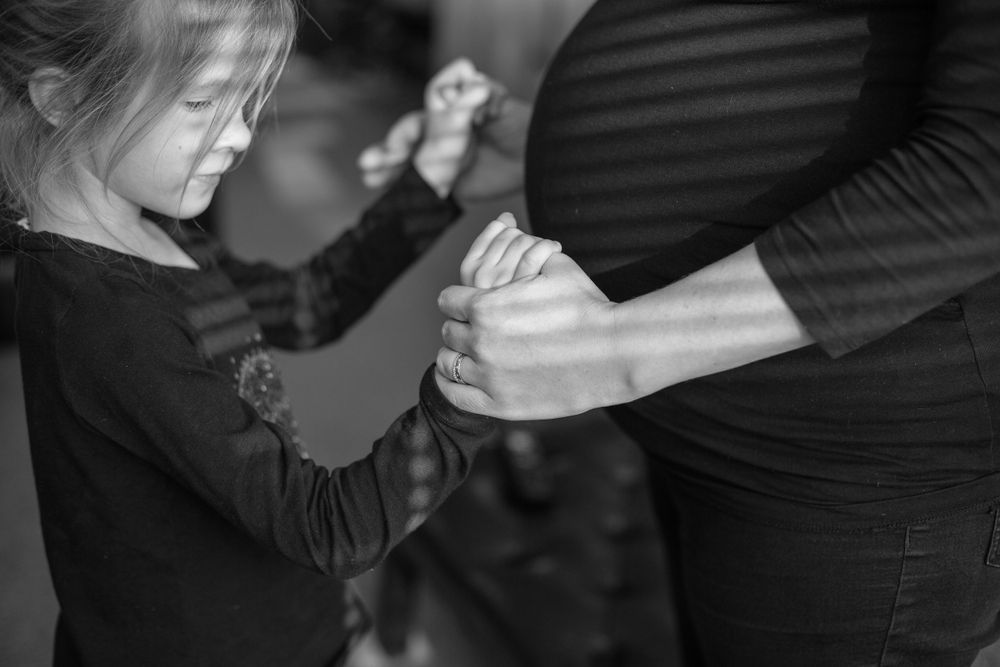 A close-up black and white image of hands touching in a tender moment.