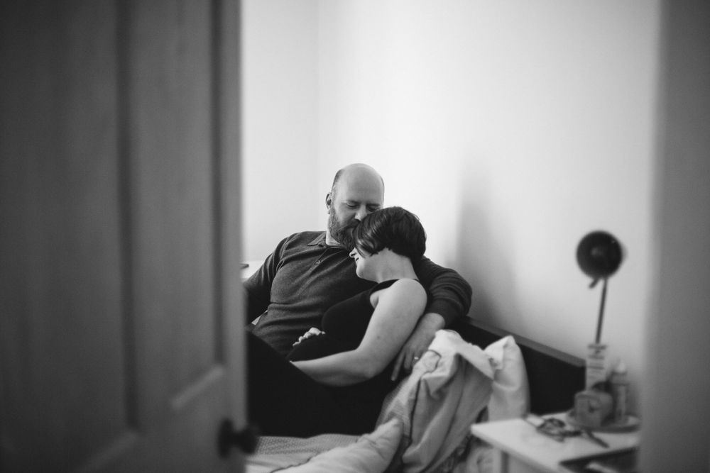 A tender moment captured in black and white showing two figures resting together on a couch.