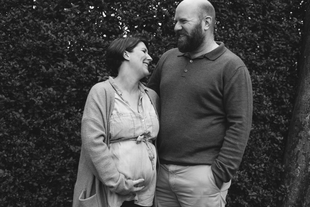 A couple shares an intimate moment outdoors as they anticipate their new arrival.