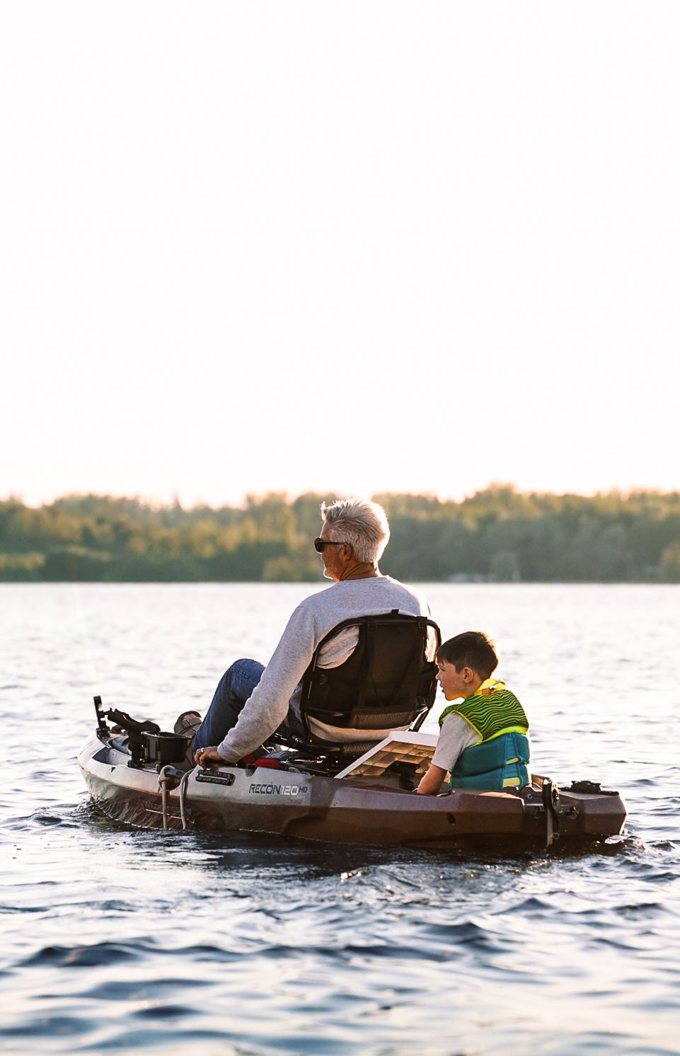 People relaxing on floating rafts in calm lake waters during late afternoon sun.