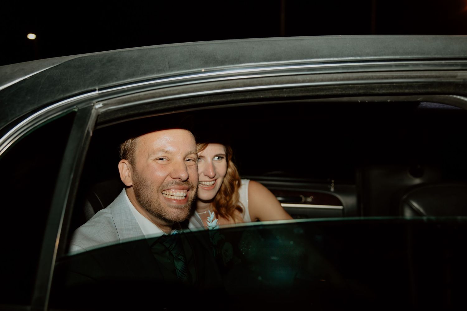A couple shares a candid moment while seated in a car at night.