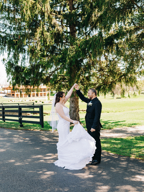 Couple dancing together under large tree branches at outdoor wedding venue.