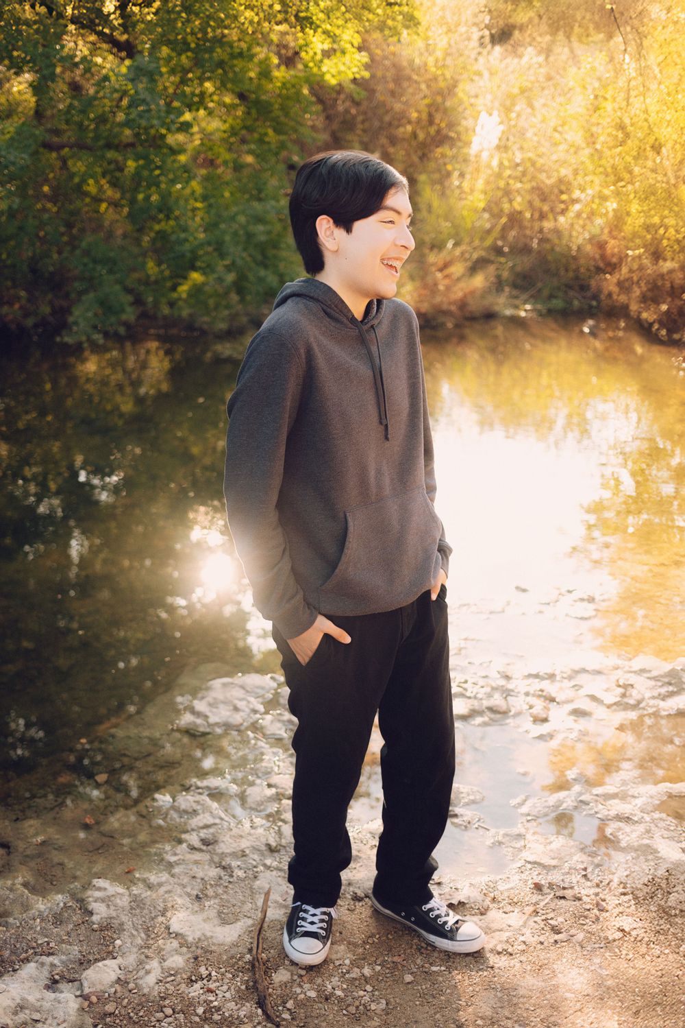 A laugh fills the golden autumn afternoon by a serene pond as sunlight streams through the trees.