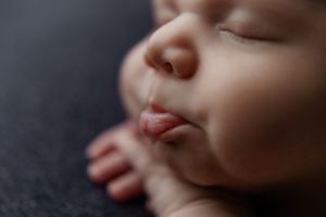 Close-up macro shot of sleeping baby's face and features against dark background in studio setting.