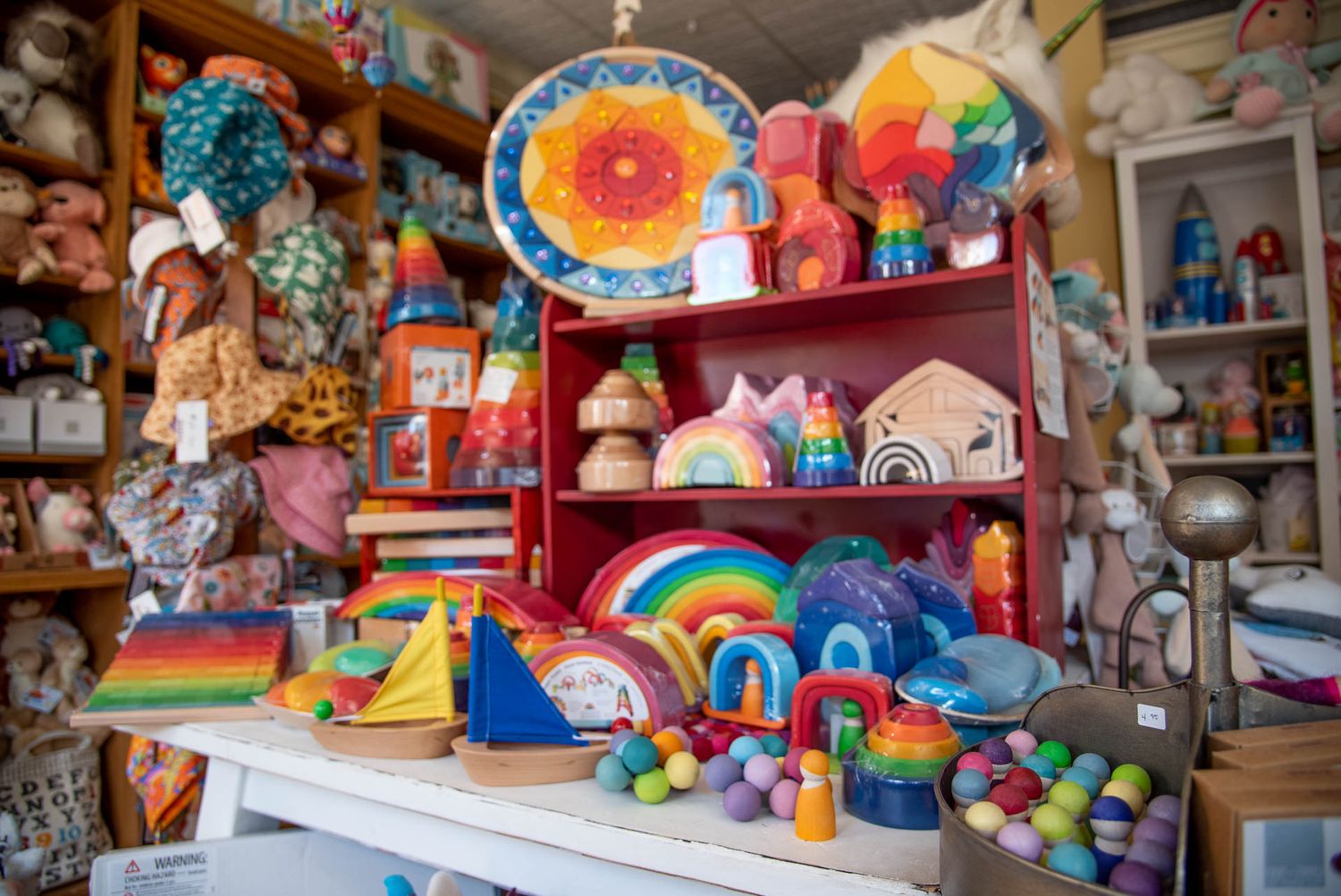 Colorful assortment of toys and rainbow decorations displayed on crowded shelves in a whimsical retail store.