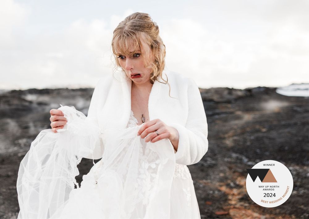 A person in a flowing white dress stands among dark rocky terrain creating dramatic contrast with the landscape.