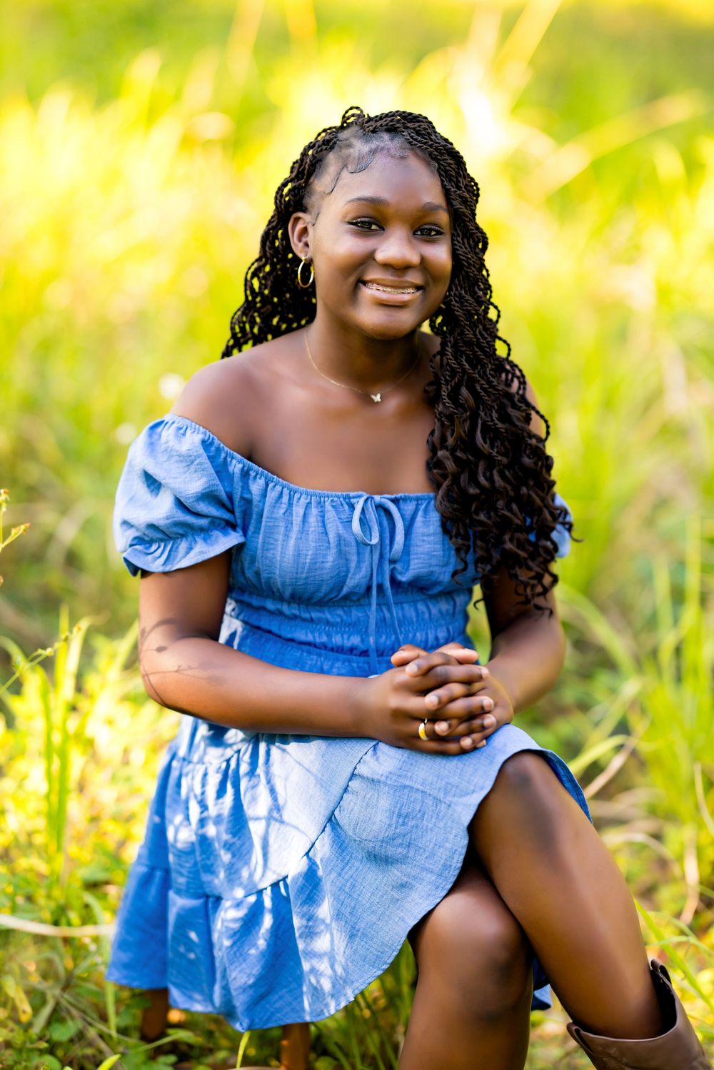 A summer portrait in a blue off-shoulder dress against golden sunlit grass.