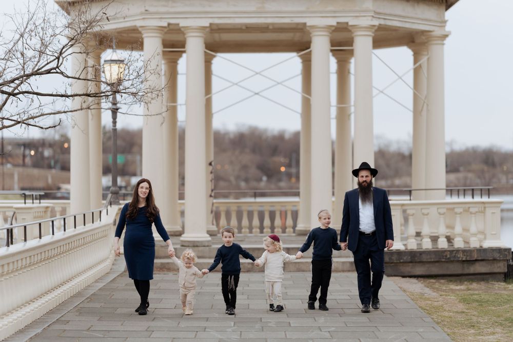 A family takes a stroll together along a grand columned pavilion walkway in winter.