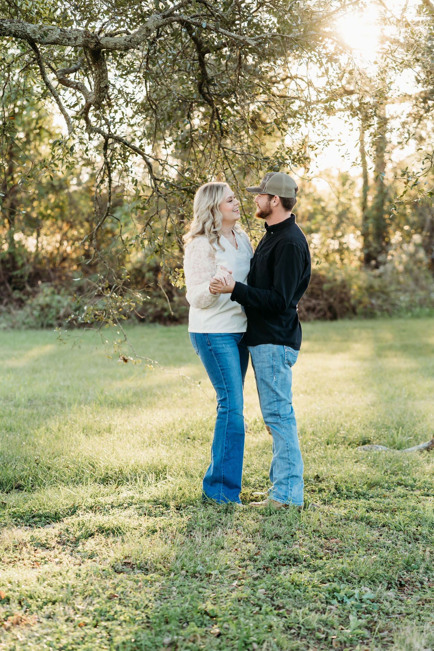 A couple shares a romantic moment in a sunlit park with trees during golden hour at sunset.