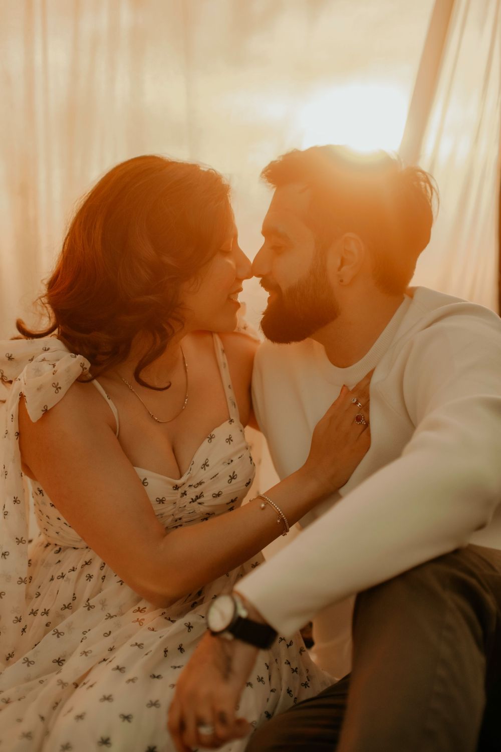 Intimate close-up of a couple in white sharing a romantic moment against a sunlit backdrop.