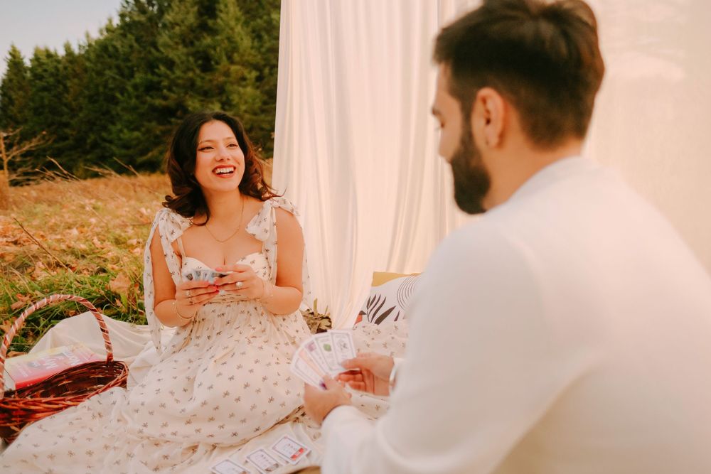 Couple enjoying a romantic outdoor picnic with wine on a white blanket in an autumn field.