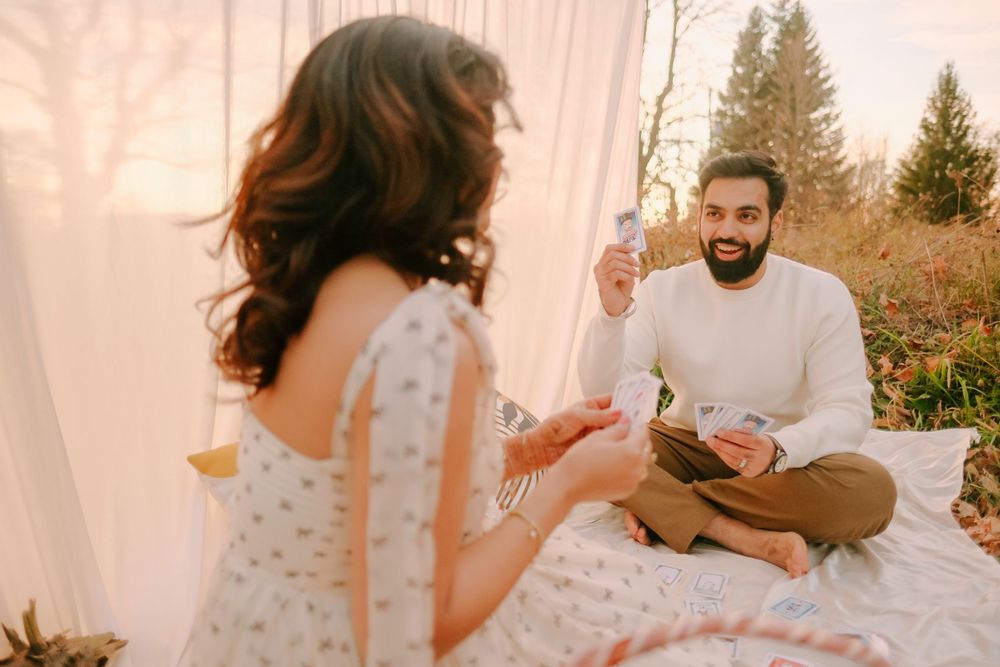 Couple enjoying picnic date while sitting on blanket with drinks and snacks in outdoor setting.