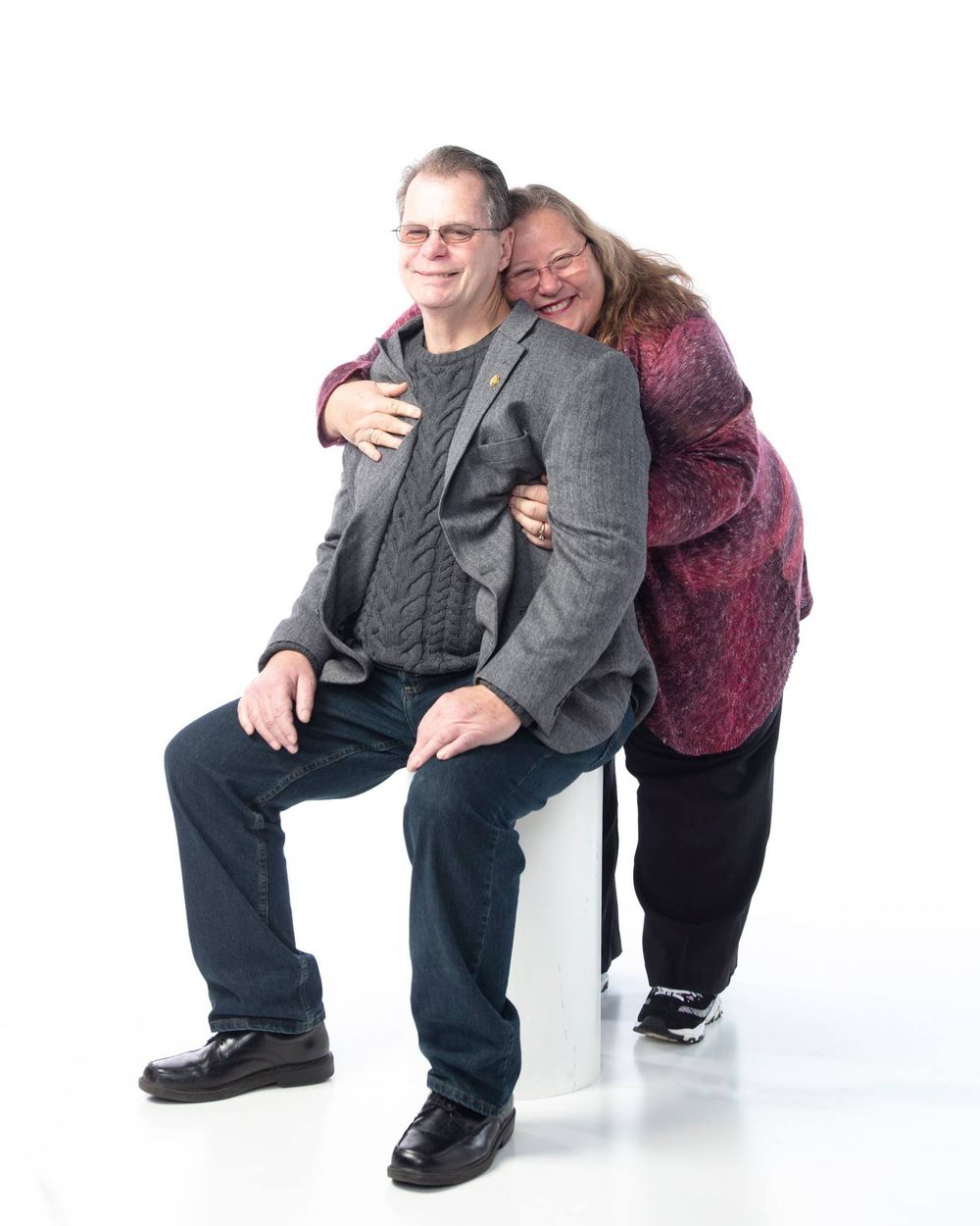 A joyful moment captured in a studio portrait against a white background showing affectionate embracing between two people.