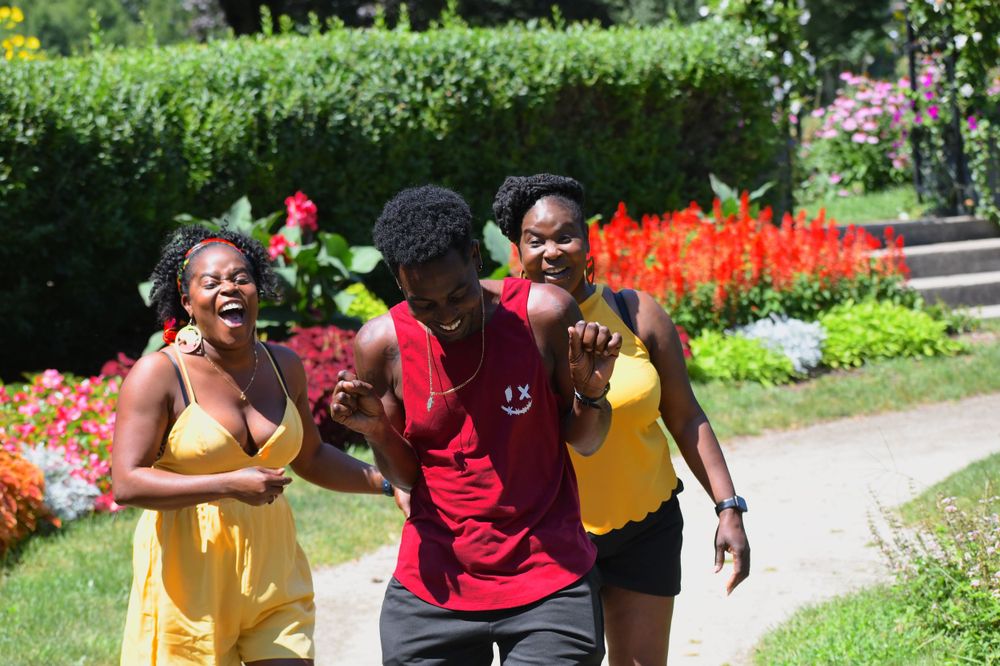 Friends laughing together in sunny garden with bright flowers.