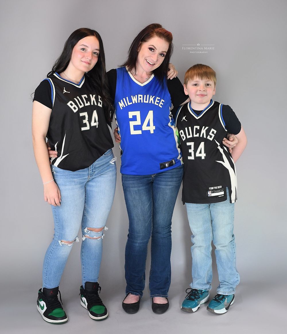 Family wearing matching Milwaukee Bucks basketball jerseys pose together in a studio setting.