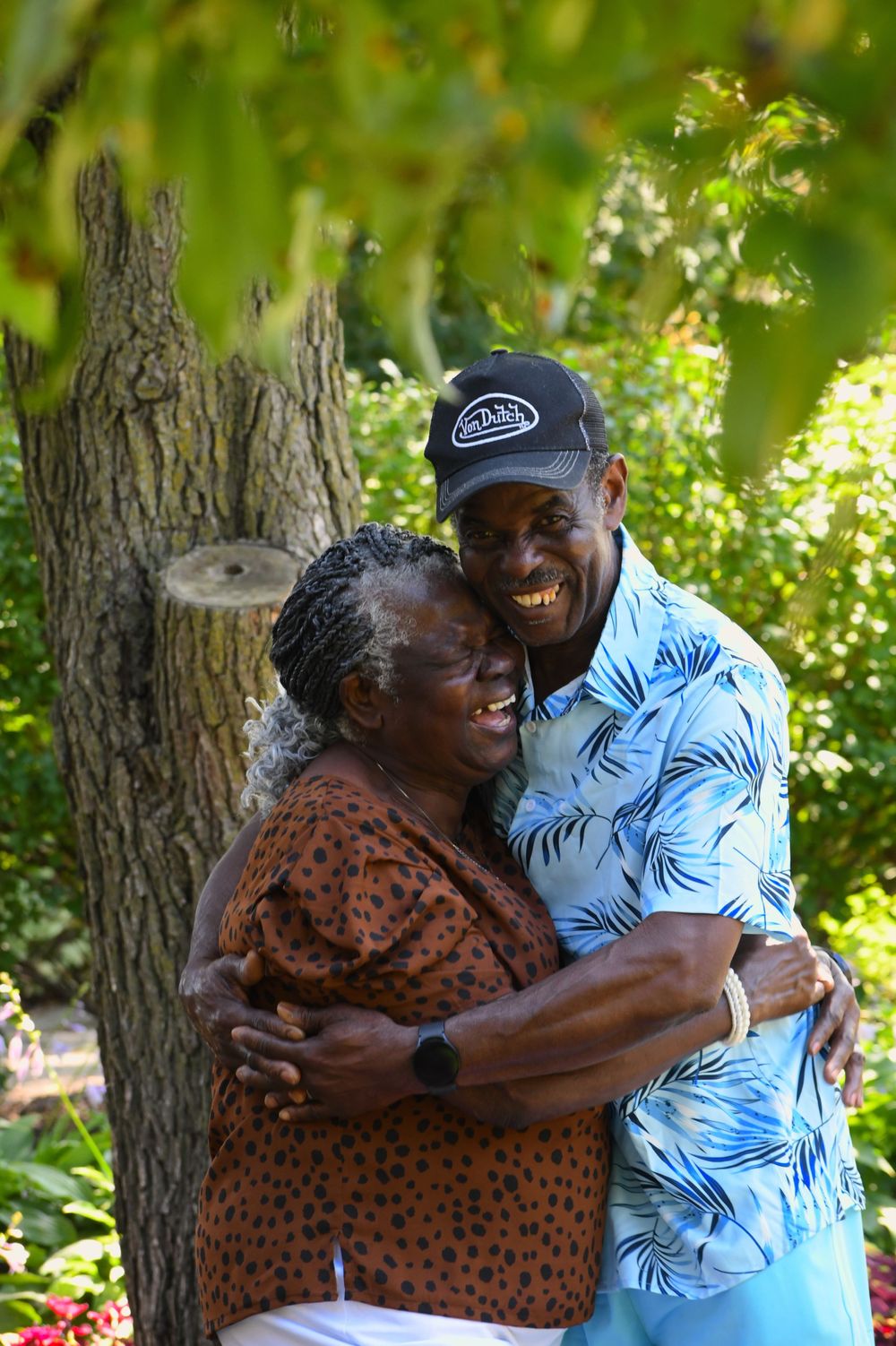 A warm embrace shared between two people in a lush garden setting on a bright sunny day.