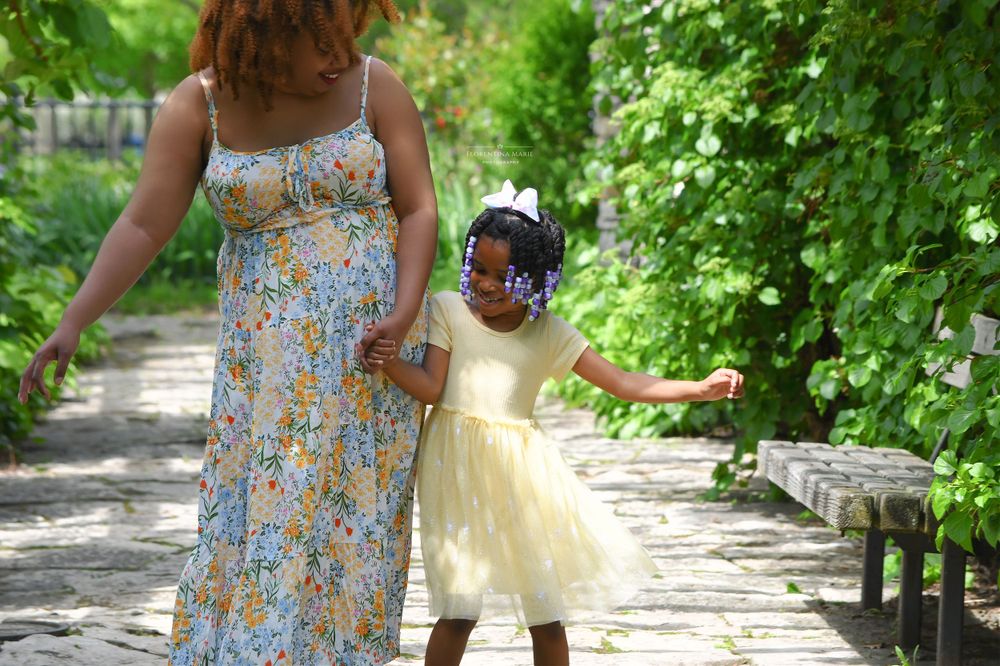 Two people walking hand in hand along a garden path surrounded by lush greenery.