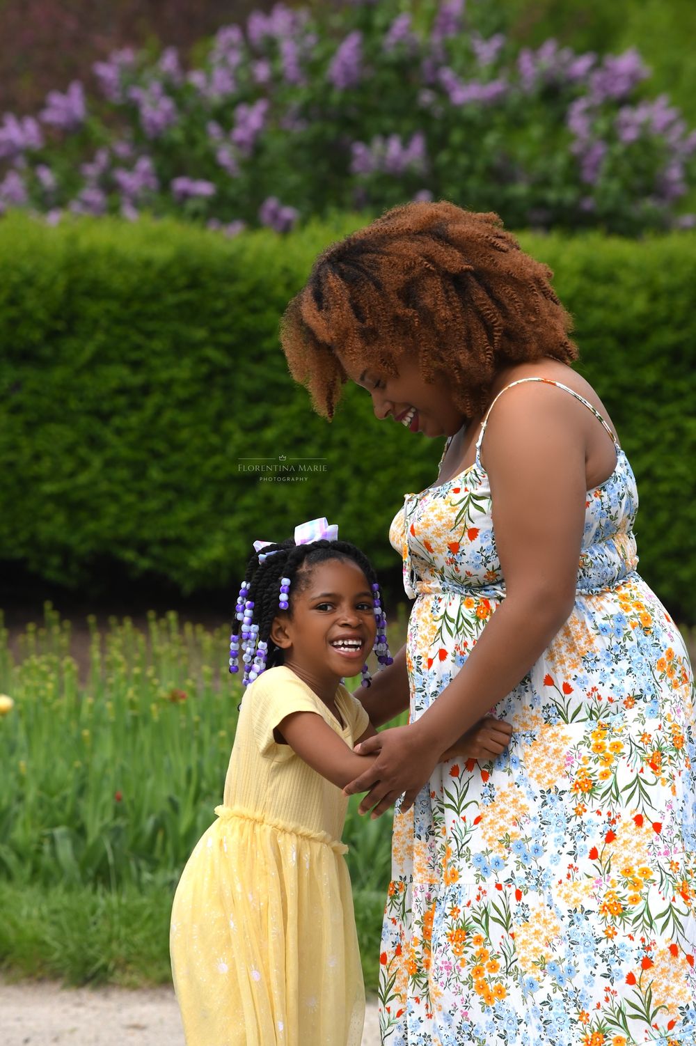 A tender moment shared between two people in a garden with purple flowers blooming in the background.