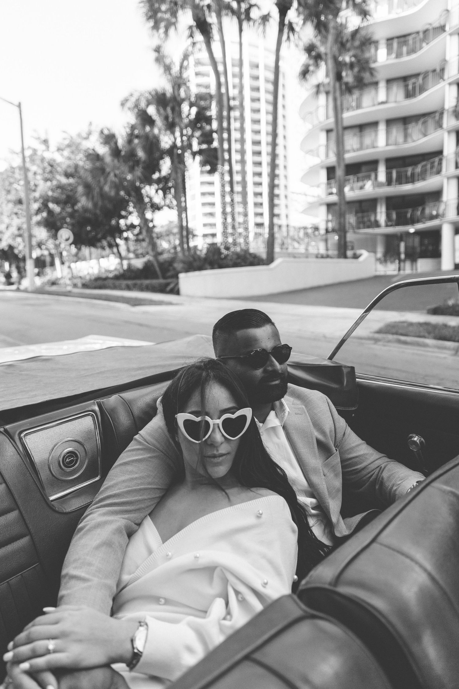 Black and white photo of people relaxing in a car's backseat.