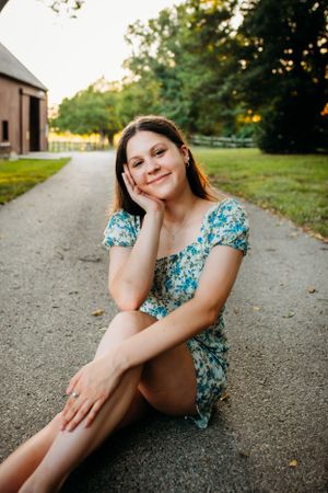 Girl smiling sitting down in road for senior portrait photography. Captured by Maryland Photographer Mallory Bramlett.