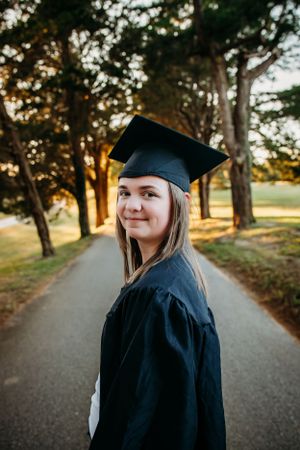 Girl in cap and gown smiling at camera for senior session photography. Captured by Maryland Photographer Mallory Bramlett.