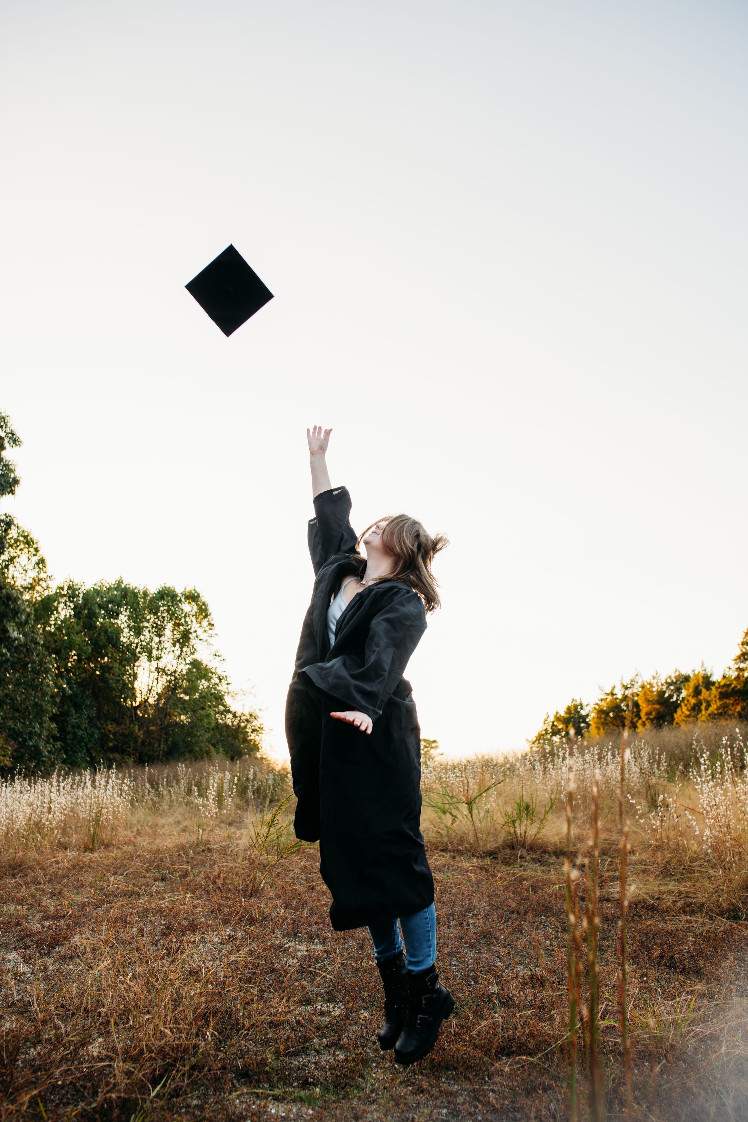 Girl throwing graduation cap in air for senior session photography. Captured by Maryland Photographer Mallory Bramlett.
