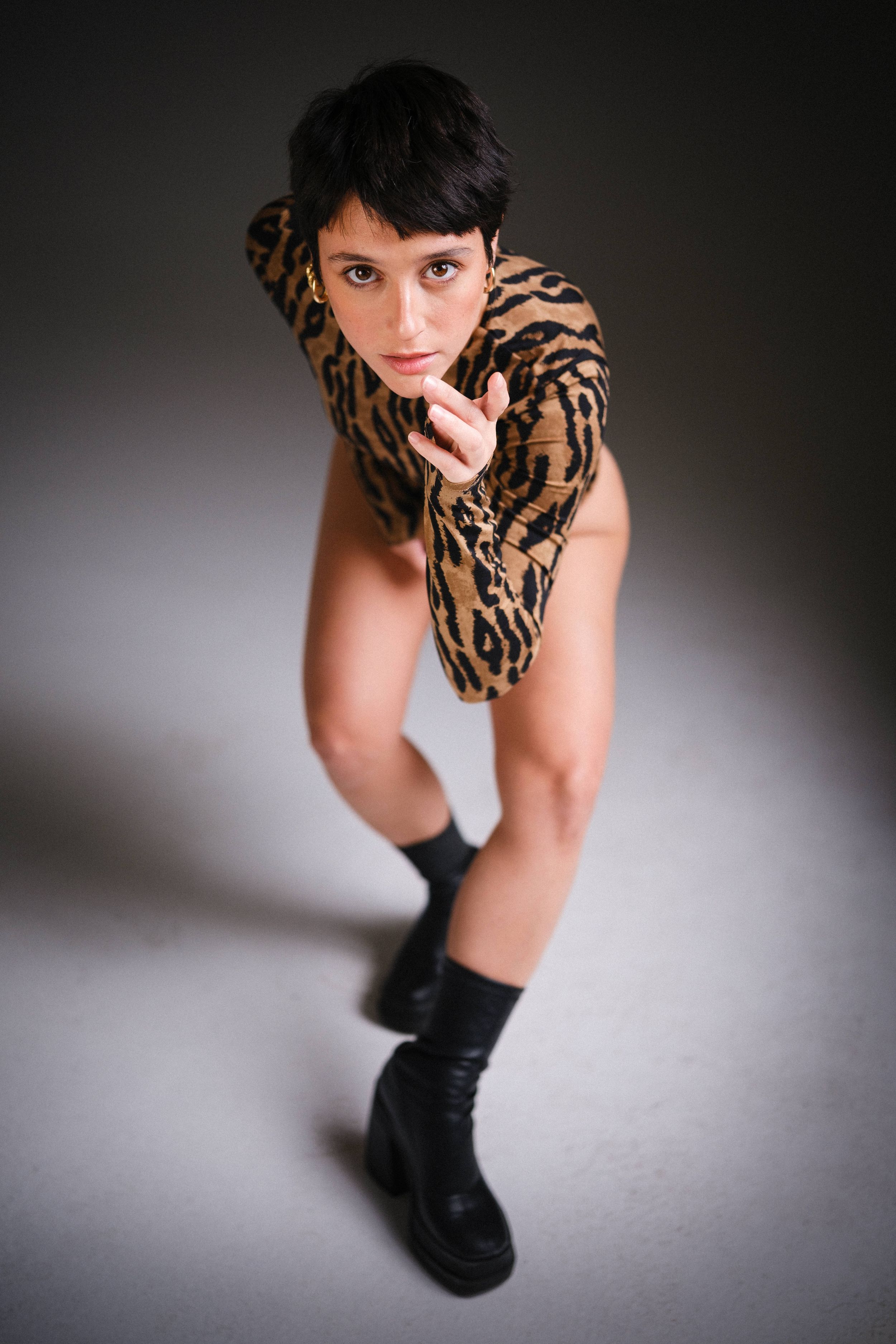 An artistic studio portrait featuring a tiger print outfit against grey backdrop.