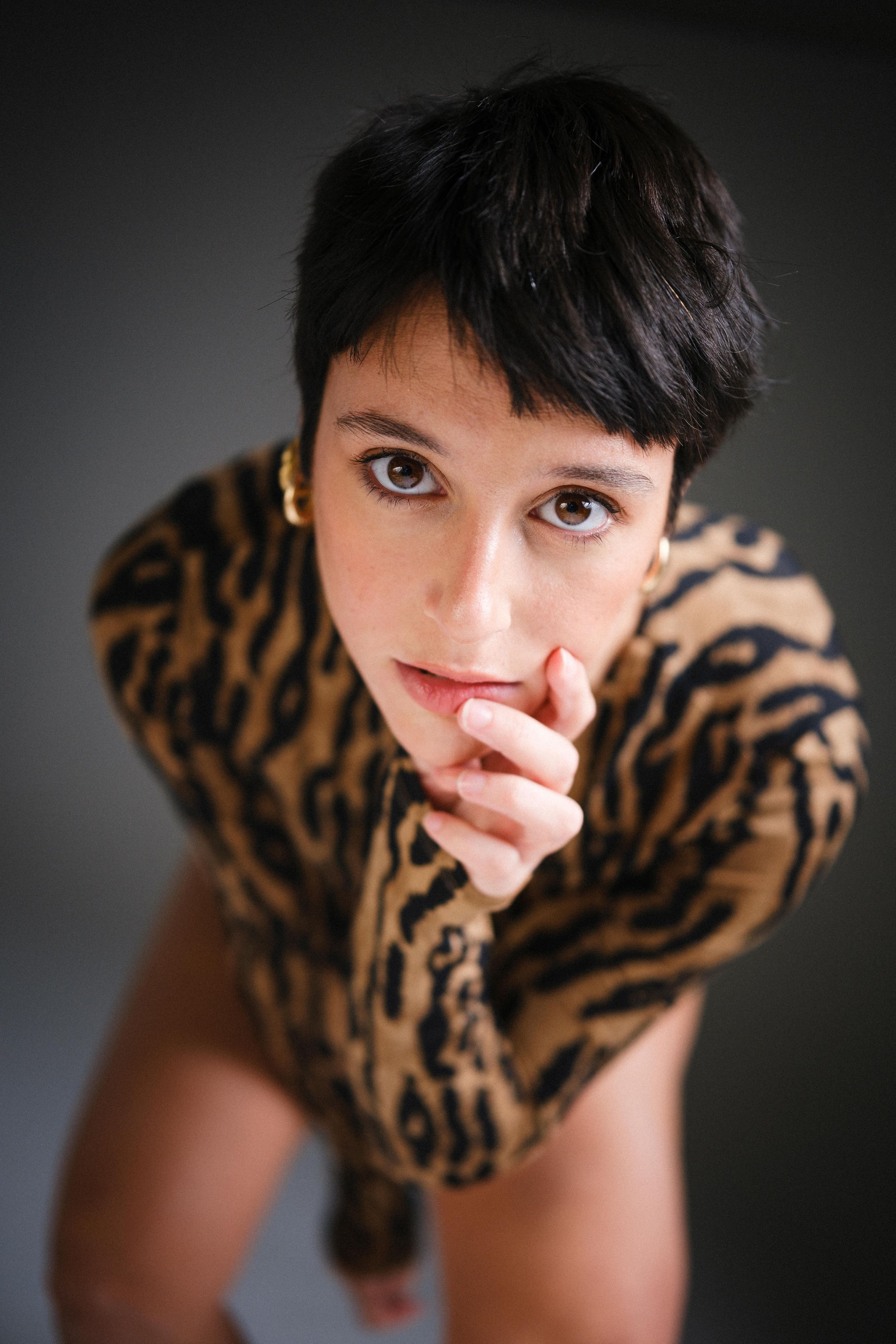 A close-up studio portrait featuring someone in a leopard print top.